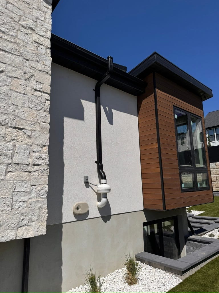 Radon Mitigation for Homeowners System Installed on Modern Home Exterior
