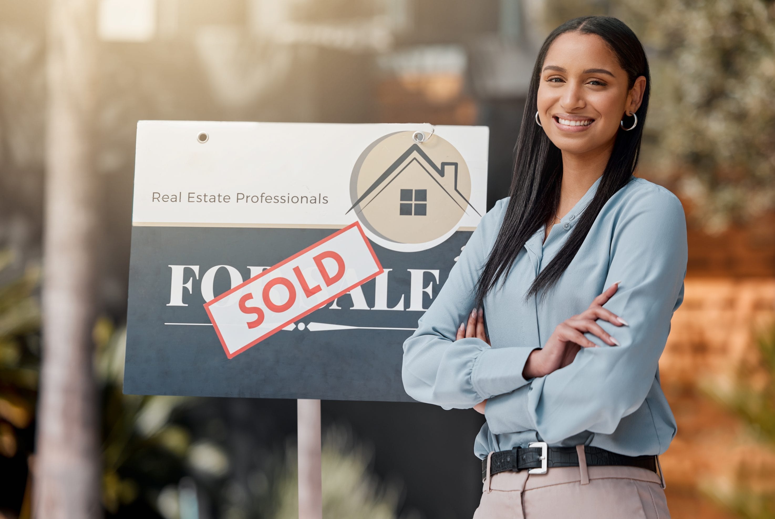 Realtor standing in front of sold property sign promoting radon mitigation for realtors
