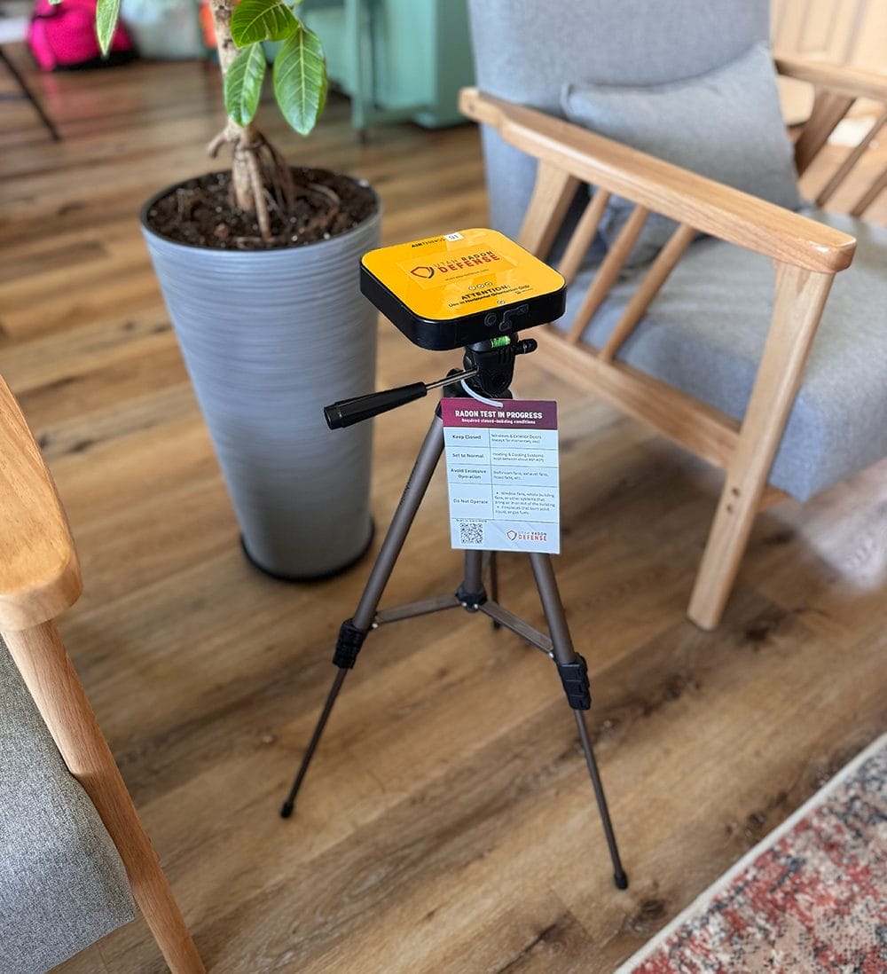 Radon testing device on tripod in living room
